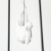 Close-up of suspended resin figure within square industrial frame